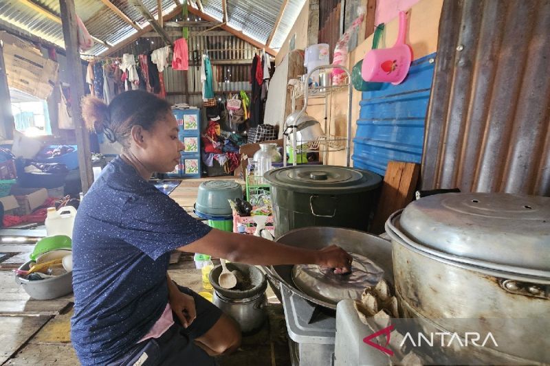 Febriani Flora Randui, anak pasangan Fedrika Karolina Wader dan Imanuel Randui, memasak di dalam rumah mereka yang tanpa penyekat ruangan, di Tanjung Ria, Kota Jayapura, Papua. (ANTARA/Qadri Pratiwi)