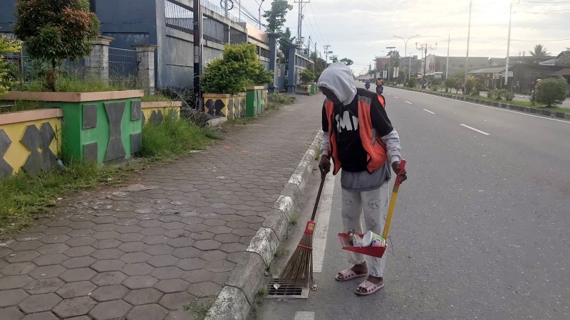 Ina saat bertugas membersikan jalan di area Petrosea, Selasa (3/1/2023). Foto: Faris/ Papua60detik